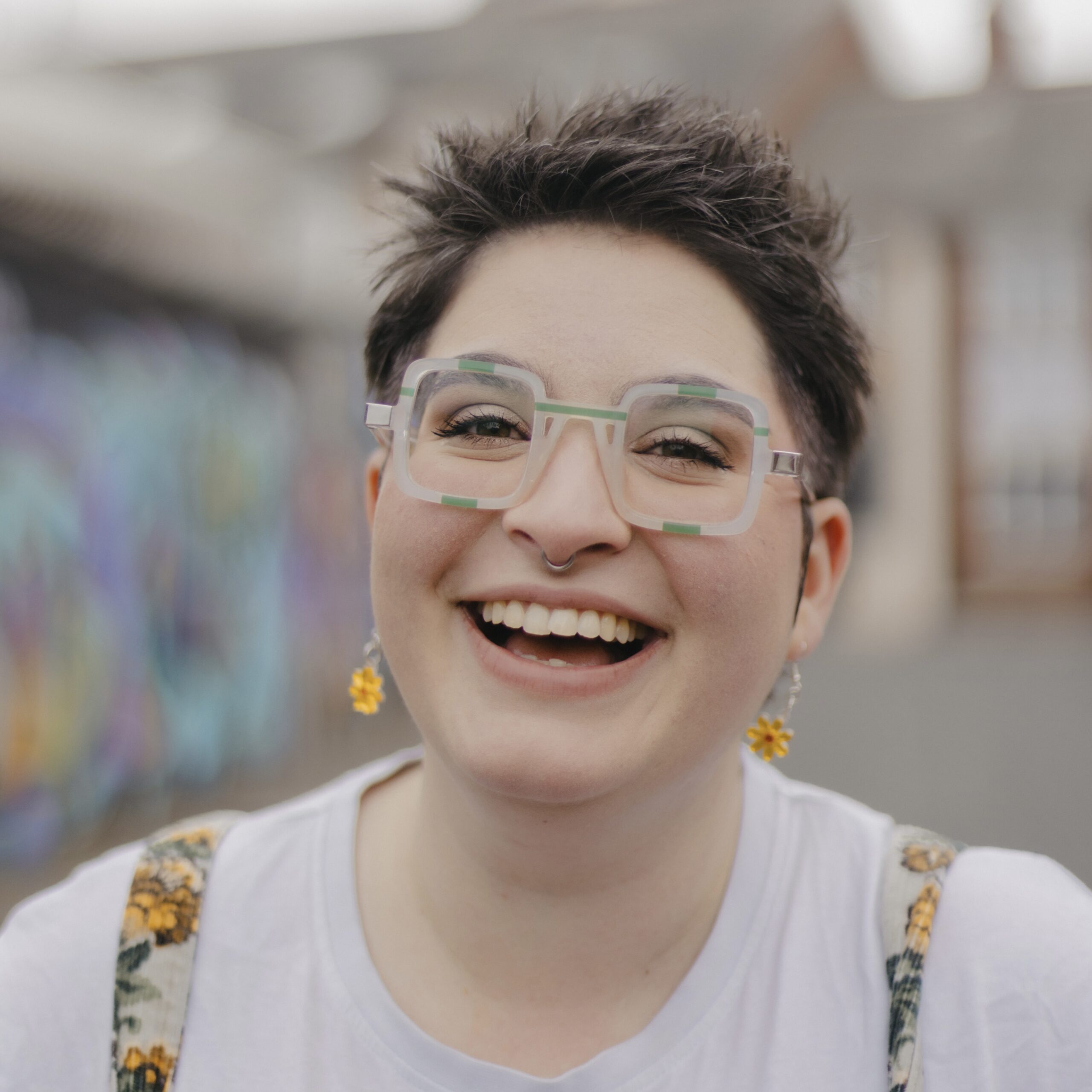 Amy Langdown, brown spiky hair and square green glasses, giving a big cheesy grin