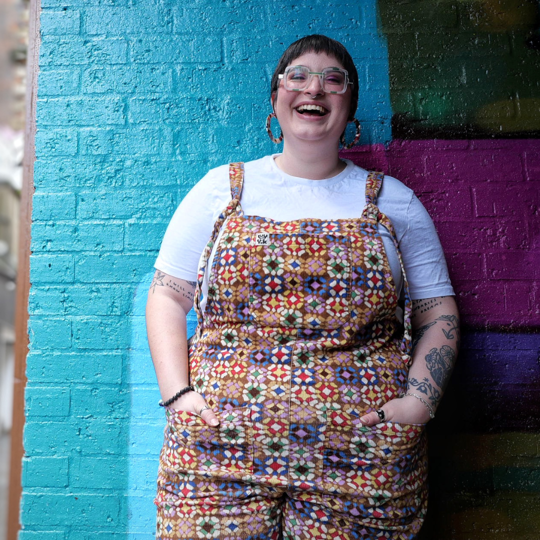 Amy Langdown, brown spiky hair and square green glasses, giving a big cheesy grin